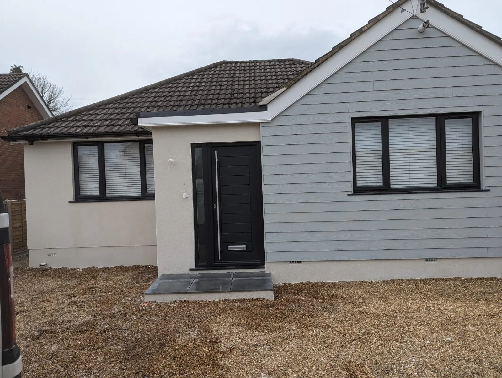 A bungalow rendered in cream beside grey cladding