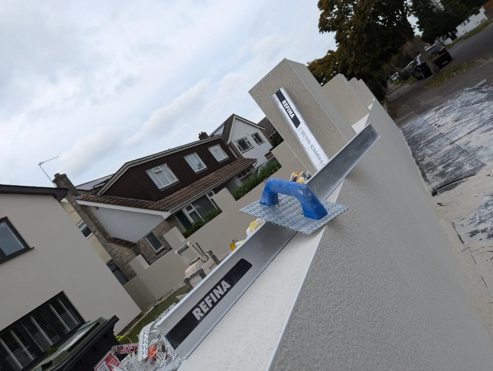 A newly rendered wall coping with Refina tools laid on it