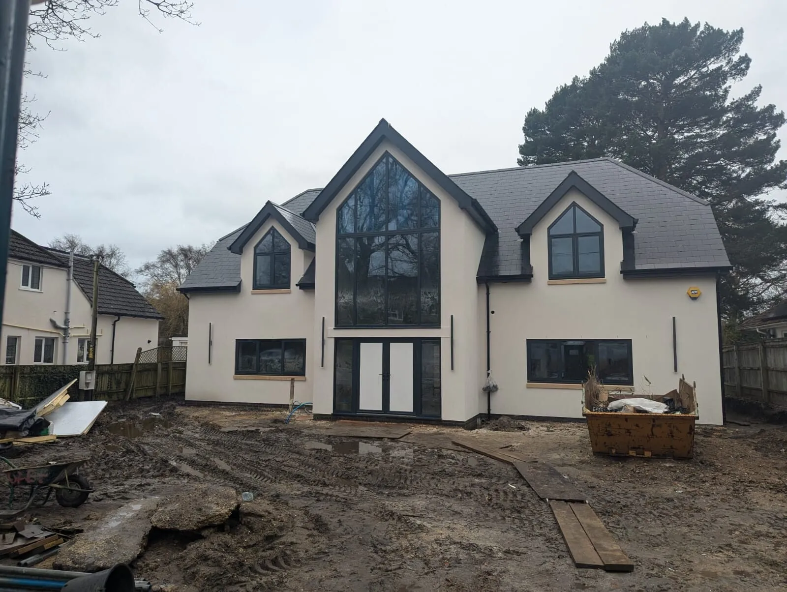 A large new build with glazed gables, finished in cream spray render by Adept